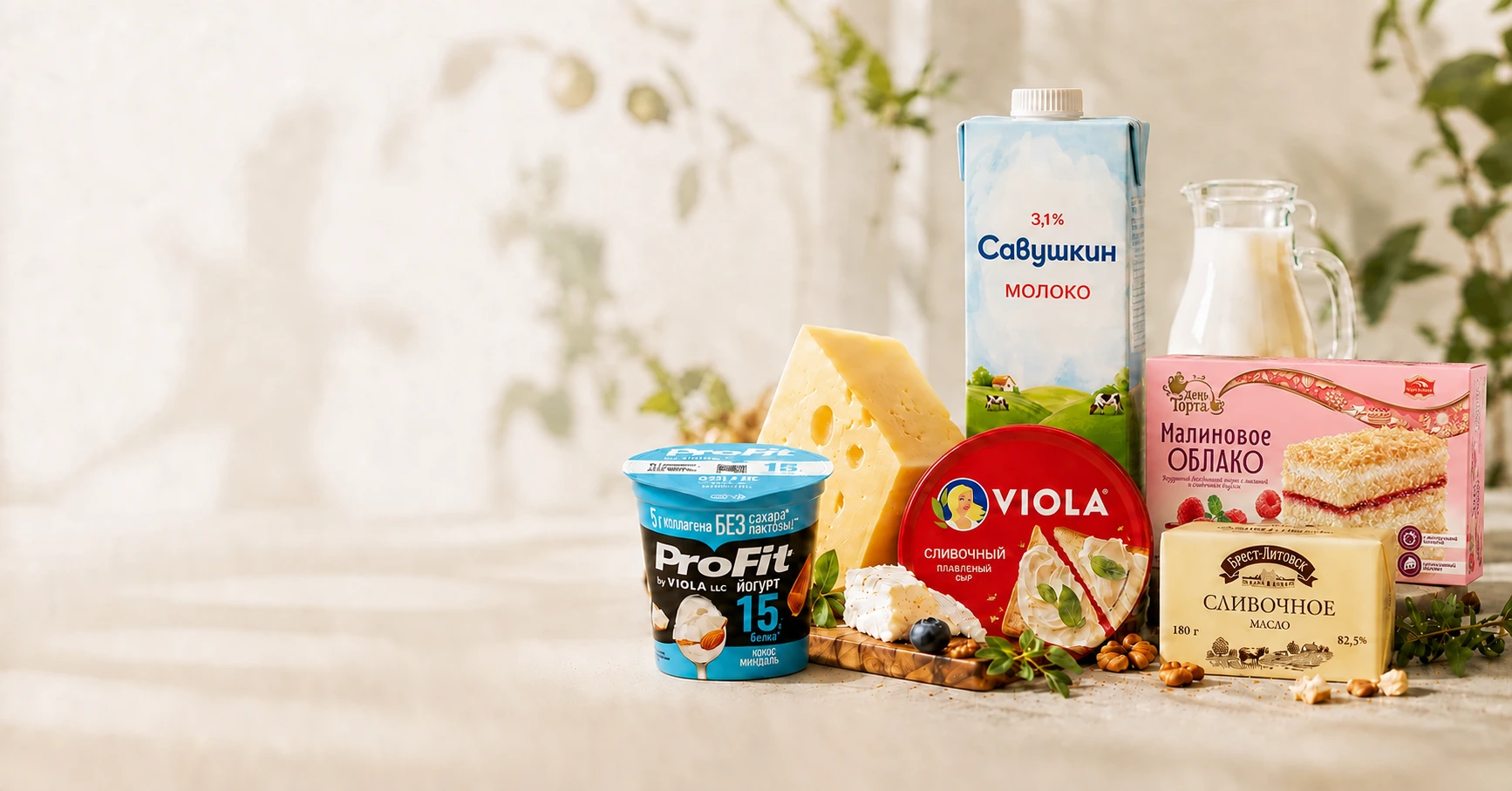 Молоко Савушкин 3,1%, сыр Viola, масло Брест-Литовск, йогурт ProFit и торт Черёмушки «Малиновое облако» в розовой упаковке на светлом столе